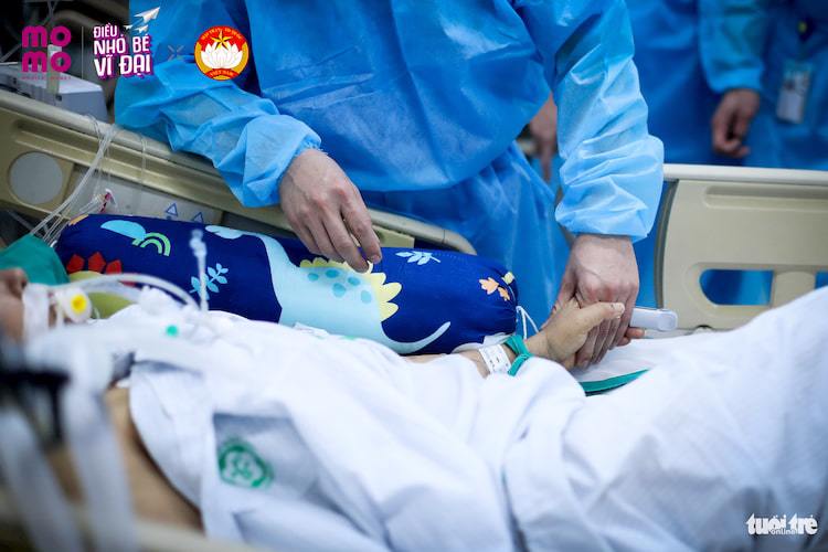 Đôi bàn tay nắm chặt của một bác sĩ và một bệnh nhân đang nằm điều trị tại khoa cấp cứu A9 Bạch Mai 